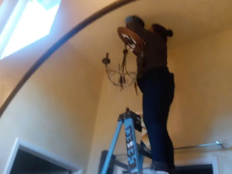 Electrician installing a chandelier in a Whitefish residence